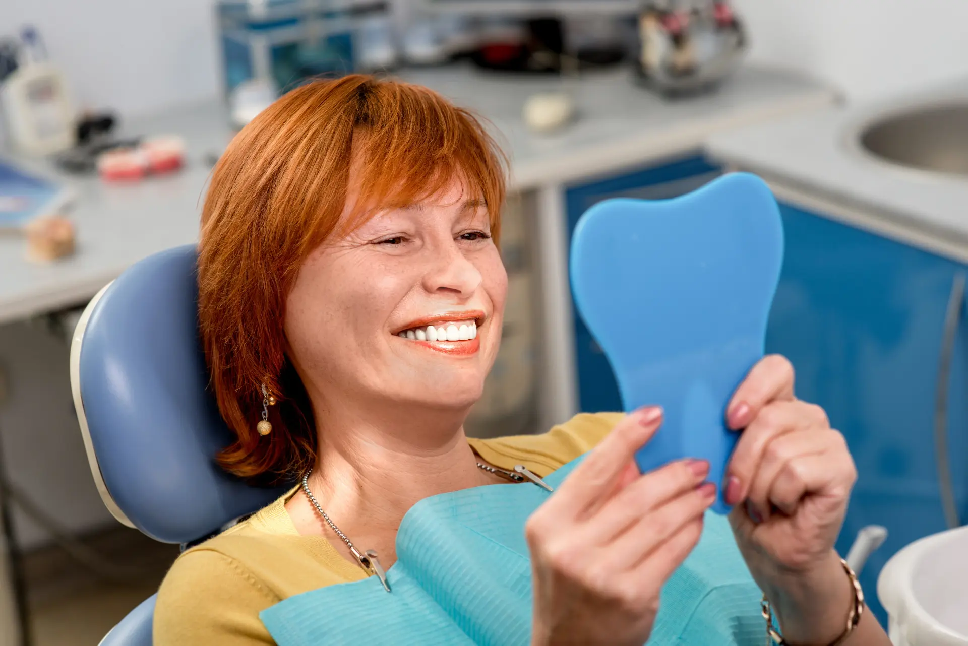 Mujer de mediana edad sonriendo a un espejo de dentista